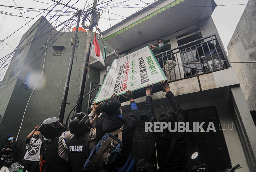 Sejumlah anggota kepolisian dan warga mencopot plang atribut FPI di Jalan Petamburan III, Jakarta, Rabu (30/12). Aparat gabungan dari TNI dan Polri mendatangi kawasan Petamburan III untuk mencabut sejumlah atribut FPI pasca pembubaran organisasi tersebut oleh pemerintah. Republika/Putra M. Akbar