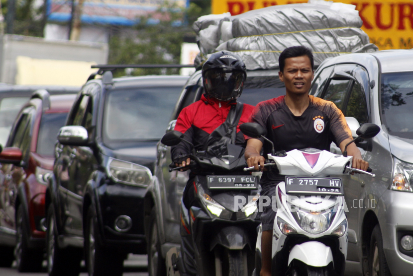 Warga mengendarai sepeda motor tanpa menggunakan helm dan masker. Ilustrasi