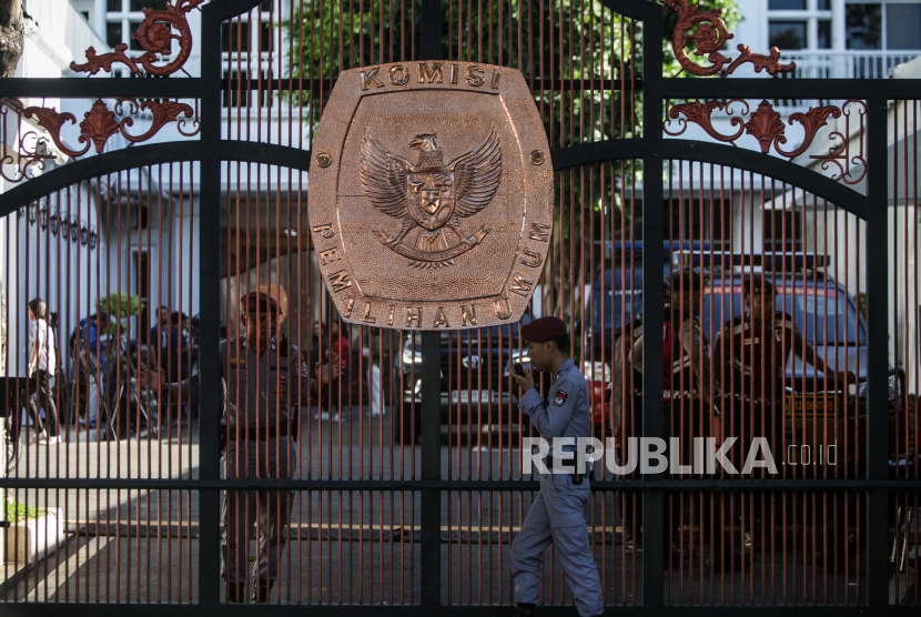 Petugas KPU berjalan di depan gerbang Gedung KPU di Jalan Imam Bonjol, Jakarta, Selasa (19/3/2024). Jelang hasil akhir proses rekapitulasi nasional Pemilu 2024 akses menuju Gedung KPU ditutup untuk peningkatan keamanan.