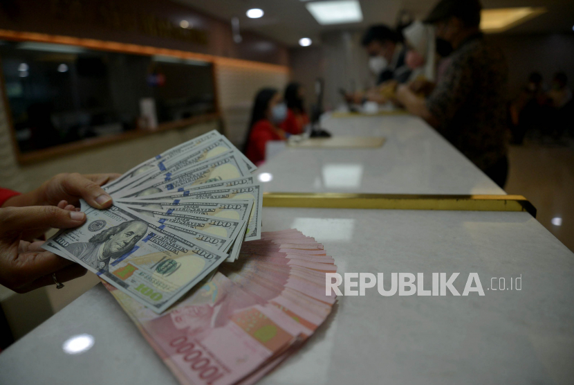 Petugas menunjukkan uang rupiah dan dolar AS di salah satu gerai penukaran mata uang asing di Jakarta, Kamis (29/9/2022).