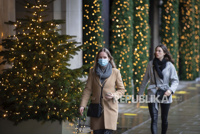 Orang-orang berjalan melewati lampu Natal di luar toko yang tutup di Oxford Street, di London. WHO minta liburan dibatalkan karena dapat meningkatkan infeksi virus corona. Ilustrasi. 