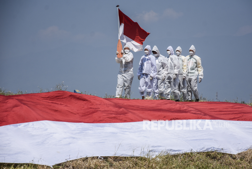 Cinta Tanah Air adalah Fitrah. Foto ilustrasi:  Relawan Covid-19 Passer membawa bendera merah putih usai mengikuti upacara HUT Kemerdekaan ke-76 Republik Indonesia di Sungai Cikijing, Rancaekek, Kabupaten Bandung, Selasa (17/8). Upacara yang diikuti oleh relawan Covid-19 Passer (Pasukan Susur Sungai dan Ekosistem Rancaekek), Unit SAR Kota Bandung, Pramuka dan Karang Taruna tersebut dalam rangka memperingati serta merayakan HUT Kemerdekaan ke-76 Republik Indonesia di masa pandemi Covid-19. Foto: Republika/Abdan Syakura