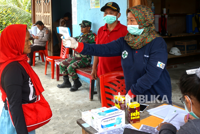 Petugas kesehatan memeriksa suhu tubuh salah satu warga di Arsopura, Distrik Skanto, Kabupaten Keerom, Papua, Senin (13/04/20). Pemerintah Kabupaten Keerom melakukan pencegahan COVID-19 melalui pemeriksaan penumpang serta penyemprotan disinfektan ke barang bawaan maupun kendaraan yang hendak masuk Kabupaten Keerom melalui pintu utama Arsopura