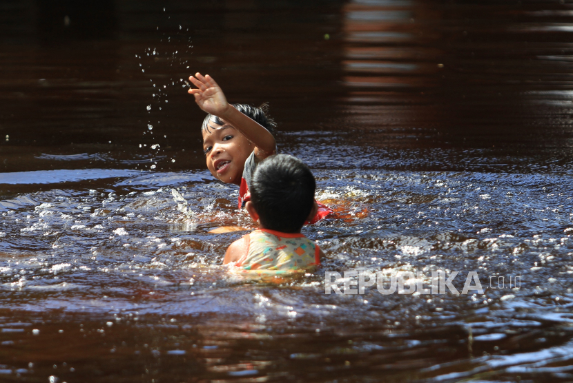 Dua anak bermain air di depan rumahnya yang terendam banjir di Desa Napai, Woyla Barat, Aceh Barat, Aceh, Kamis (16/11/2023). Banjir yang disebabkan tingginya intensitas hujan dan meluapnya sungai Krueng Woyla itu merendam sebagian rumah warga di Kecamatan Arongan Lambalek dan Kecamatan Woyla Barat.  