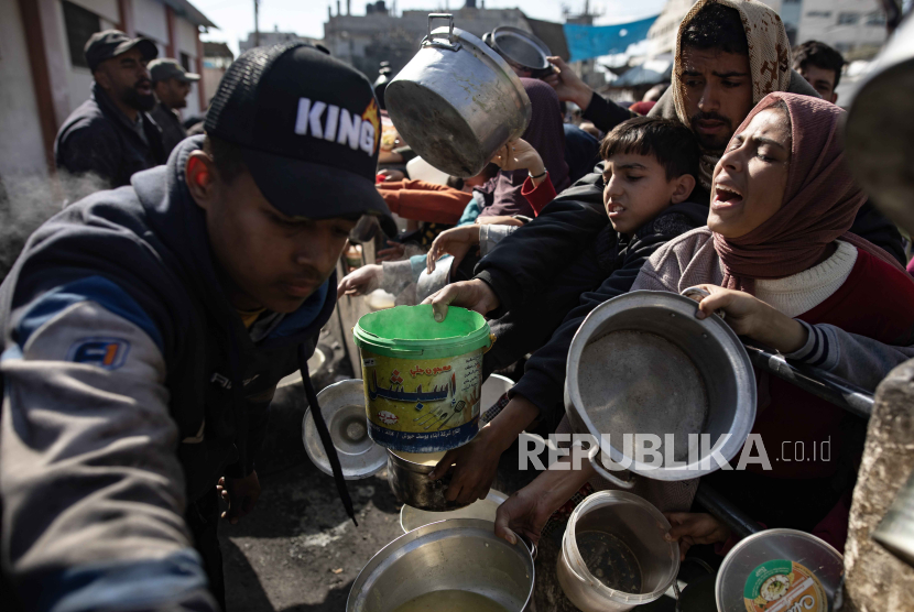 Warga Palestina yang mengungsi memegang panci dan ember kosong saat menunggu menerima bantuan makanan yang diberikan oleh kelompok pemuda Palestina di kamp pengungsi Rafah, Jalur Gaza Selatan, (25/1/2024).