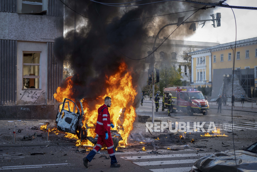 Seorang pekerja medis berlari melewati mobil yang terbakar setelah serangan Rusia di Kyiv, Ukraina, Senin, 10 Oktober 2022.