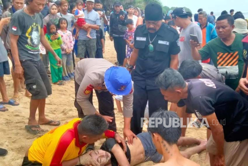 Petugas melakukan penyelamatan terhadap wisatawan yang dilaporkan terseret ombak di Pantai Karang Papak, Kecamatan Cikelet, Kabupaten Garut, Senin (1/1/2024). 