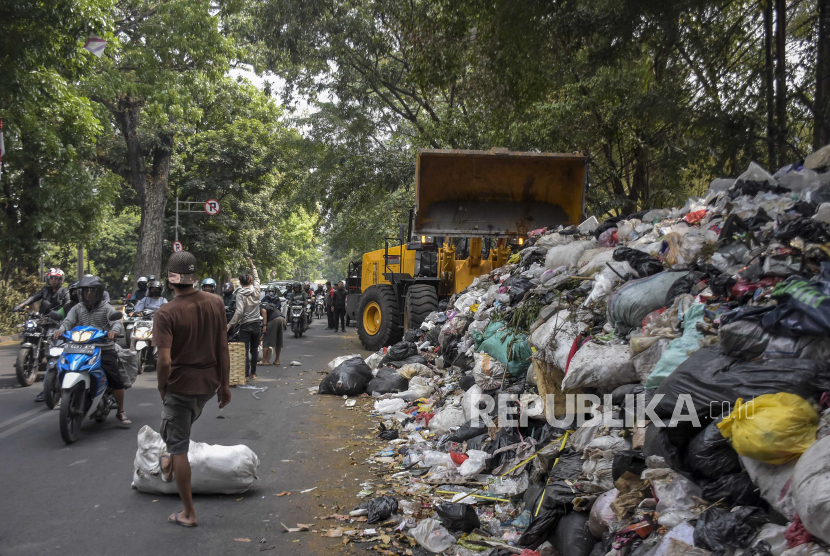 Pekerja menggunakan alat berat membersihkan sampah yang menumpuk di TPS Tegallega, Kota Bandung, Jawa Barat, Kamis (12/10/2023). 