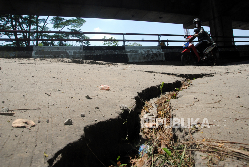 Pengendara sepeda motor melintas di ruas jalan nasional yang mengalami penurunan tanah sedalam 50 sentimeter di Jalan KH Sholeh Iskandar, Kota Bogor, Jawa Barat, Selasa (4/1/2022). 