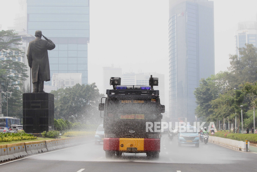 Mobil kepolisian menyemprotkan air di Jalan Jenderal Sudirman, Jakarta, Rabu (23/8/2023). Penyemprotan di sekitar jalan protokol tersebut sebagai upaya untuk membersihkan debu-debu yang bertebaran di jalanan akibat polusi udara.