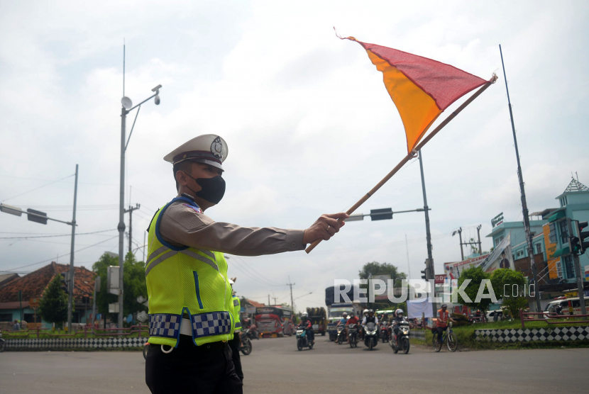 Anggota polisi mengatur arus kendaraan di Pos Perempatan Palimanan, Cirebon.