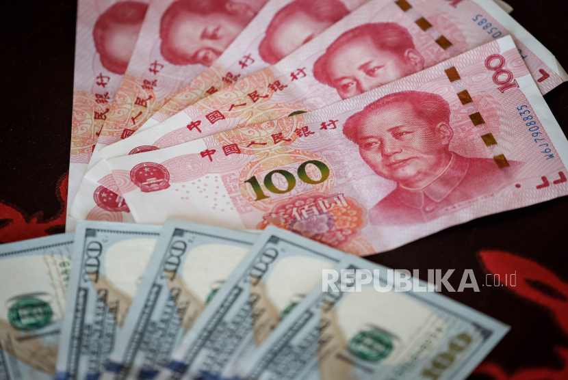 Uang kertas 100 yuan China atau Renminbi (RMB) dan dolar AS duduk di atas meja di Beijing, China, 29 September 2022. 
