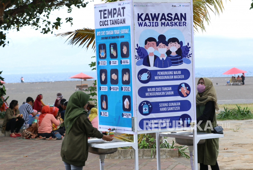 Pengunjung mencuci tangan ditempat yang disediakan di Pantai Boom, Banyuwangi, Jawa Timur, Ahad (21/6/2020). Setelah mendapatkan sertifikat normal baru dari  dinas kesehatan setempat, wisata Pantai Boom mulai membuka simulasi kunjungan wisatawan