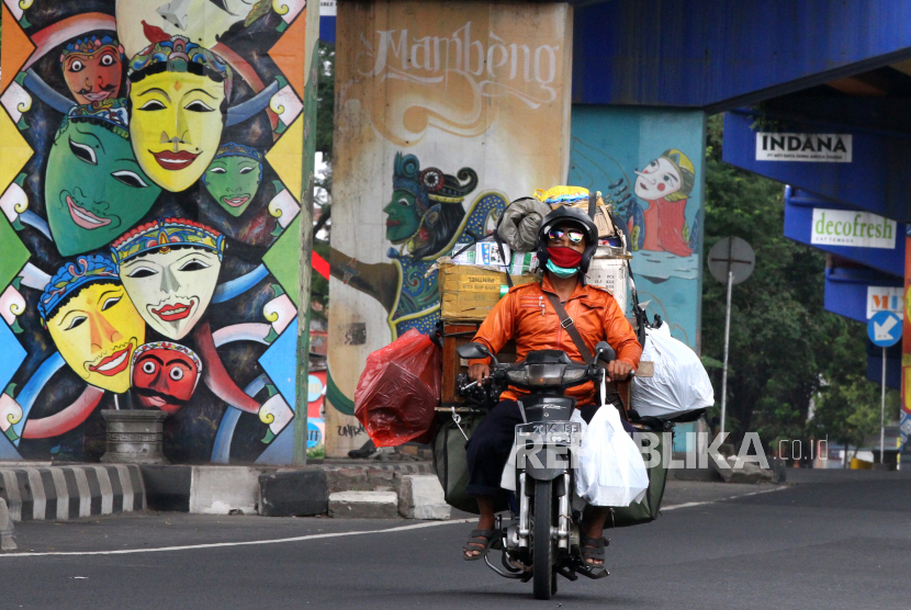 [ilustrasi] Pengendara motor melintas di depan mural topeng malangan saat pemberlakuan Pembatasan Sosial Berskala Besar (PSBB) hari pertama di Jalan Raya Ahmad Yani, Malang, Jawa Timur.