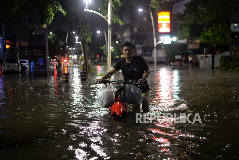 Pengendara mendorong motornya saat menerobos banjir di Jalan Kemang Raya, Jakarta Selatan, Selasa (5/10/2022). Banjir setinggi kurang lebih satu meter tersebut terjadi akibat dari luapan Kali Krukut setelah hujan deras pada sore hari, hingga malam hari pukul 20.36 WIB banjir tersebut belum surut. Republika/Thoudy Badai