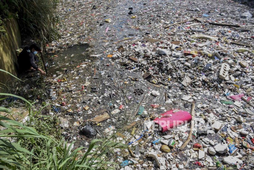 Seorang warga memilah sampah plastik dari tumpukan sampah yang memenuhi sungai (ilustrasi)