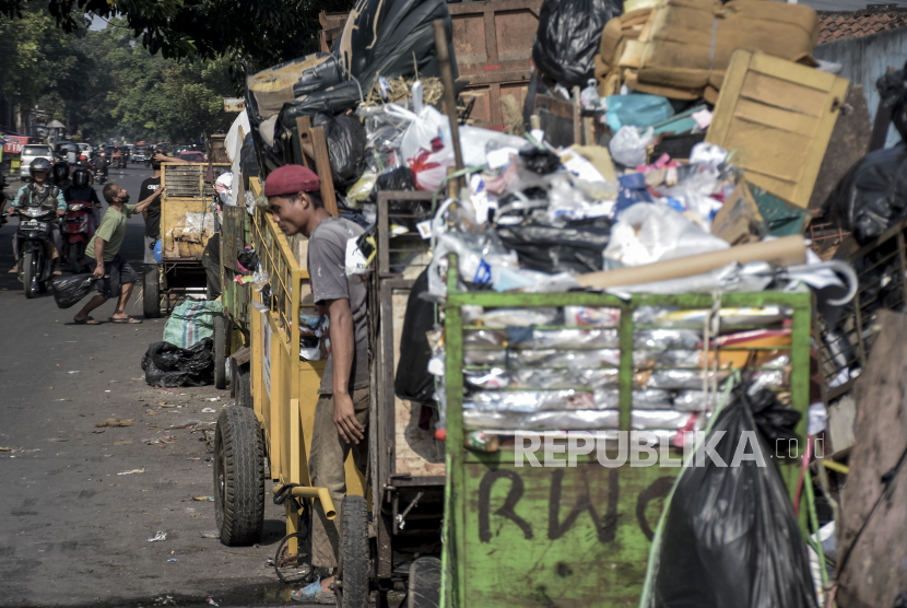 Petugas pengangkut sampah beraktivitas di antara tumpukan sampah di Jalan Pagarsih, Astanaanyar, Kota Bandung, Ahad (15/1/2023). 