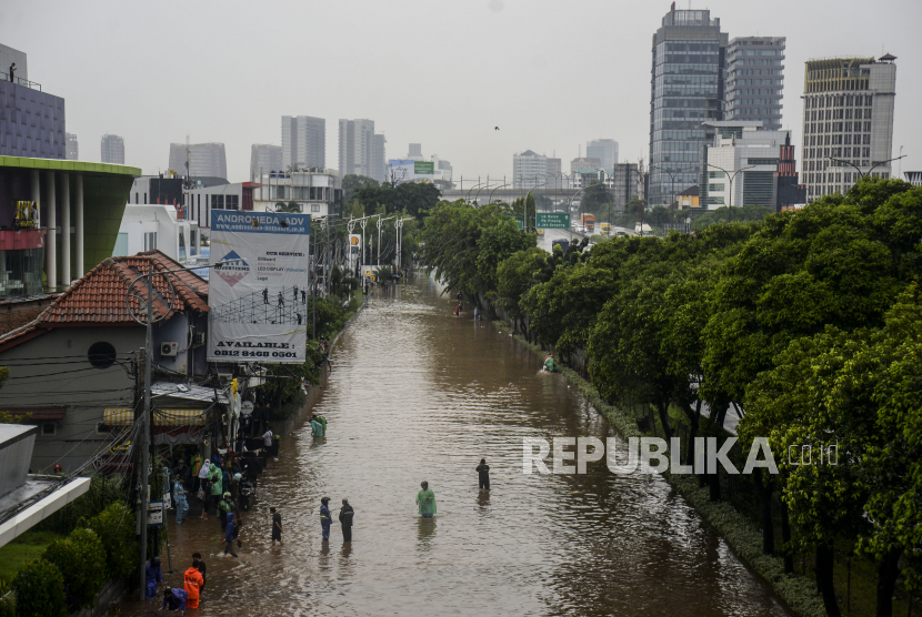 Warga berjalan melewati banjir di Jalan TB Simatupang, Jakarta, Kamis (6/10/2022). Banjir yang diakibatkan tingginya curah hujan membuat akses lalu lintas di jalan protokol tersebut lumpuh. Republika/Putra M. Akbar