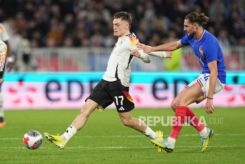 Pemain Prancis Adrien Rabiot berebut bola dengan pemain Jerman Florian Wirtz pada pertandingan sepak bola persahabatan internasional antara Prancis dan Jerman di stadion Groupama di Decines, Lyon, Ahad (24/3/2024) WIB. Pada pertandingan itu Prancis kalah dengan skor 2-0. Gol Prancis dicetak Florian Wirtz di menit pertama dan Kai Havertz di menit ke-49.