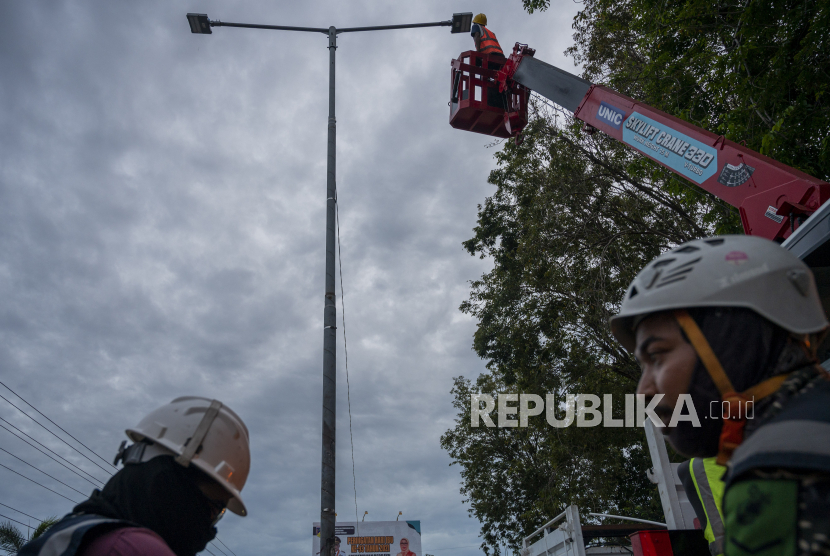 Pekerja mengganti bola lampu Penerangan Jalan Umum (PJU) di salah satu ruas jalan di Palu,, Sulawesi Tengah, Rabu (22/12/2021). (Ilustrasi)