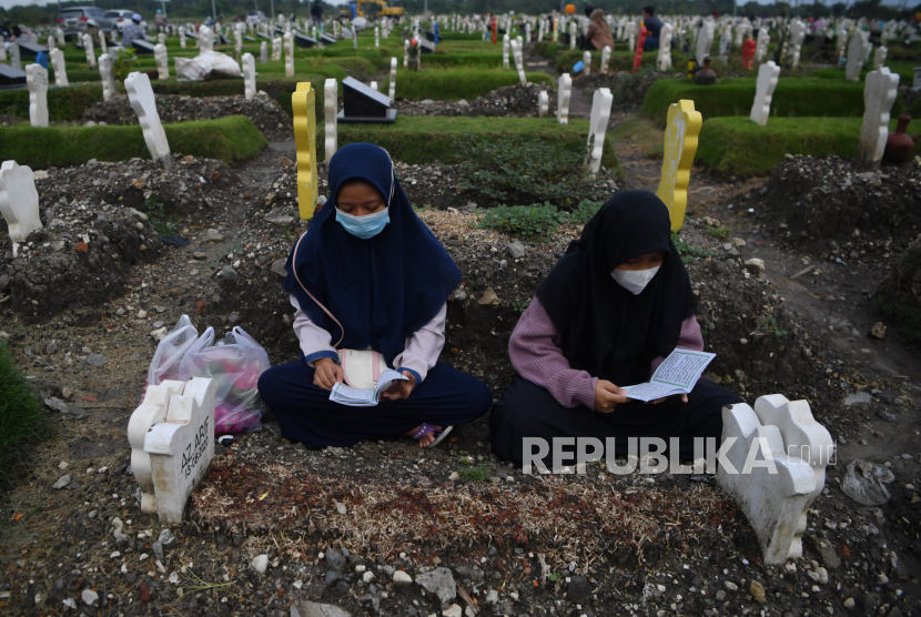 Warga berdoa saat melakukan ziarah di kuburan  khusus kasus COVID-19 di TPU Keputih di Surabaya, Jawa Timur, Kamis (21/1/2021). Berdasarkan data Satuan Tugas Penanganan COVID-19 pada Kamis (21/1), jumlah kasus terkonfirmasi positif COVID-19 bertambah 11.703 sehingga total positif menjadi 951.651 dan kasus pasien COVID-19 yang meninggal dunia bertambah 346 orang, sehingga total menjadi 27.203 orang.