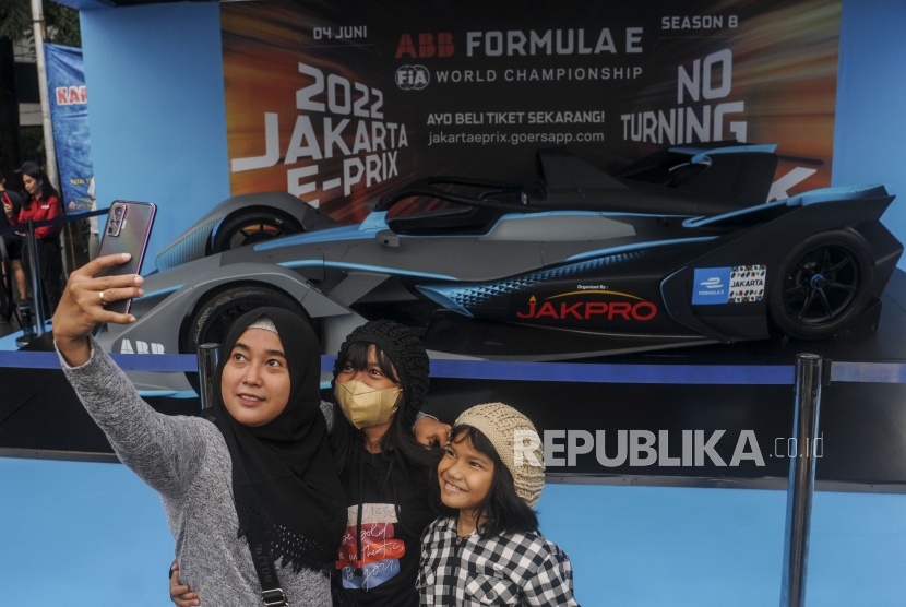 Sejumlah warga berfoto dengan replika mobil Formula E saat Car Free Day di kawasan Bundaran HI, Jakarta, Ahad (29/5/2022). Replika mobil berteknologi ramah lingkungan itu dipamerkan untuk mengkampanyekan perhelatan Formula E yang akan berlangsung pada 4 Juni 2022. 