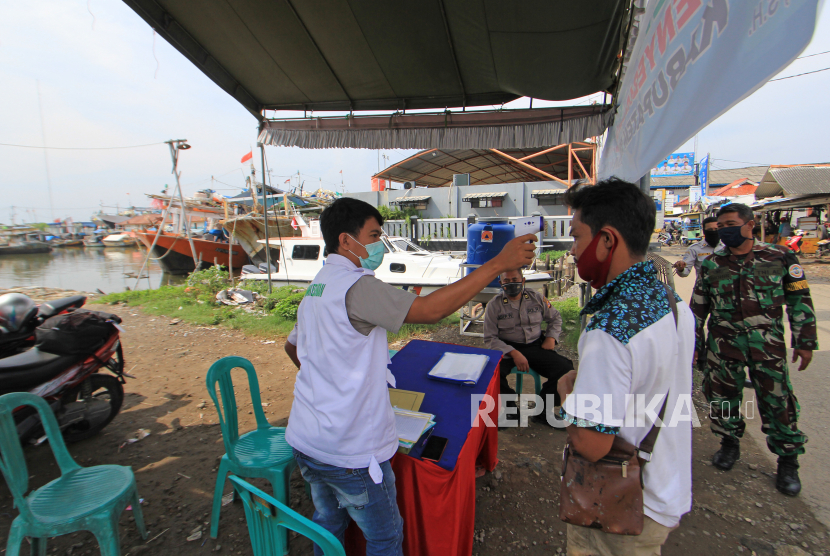Petugas memeriksa suhu tubuh warga di pos pemeriksaan (check point) pelabuhan perikanan, Karangsong, Indramayu, Jawa Barat, Rabu (6/5/2020). Pemeriksaan tersebut sebagai upaya penyekatan dan mencegah penyebaran virus COVID-19 terhadap nelayan yang pulang melaut