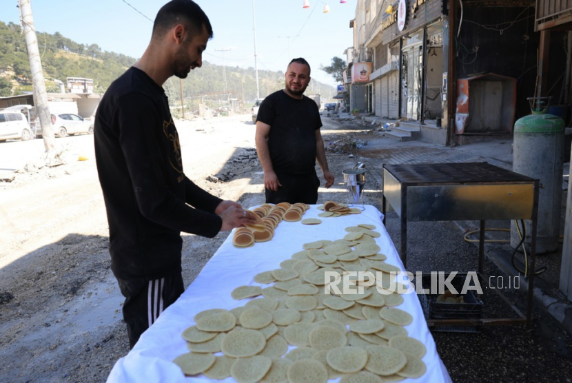 Seorang pedagang Palestina menjual Qatayef pada hari pertama bulan suci Ramadan, di kamp pengungsi Nur Shams dekat kota Tulkarem di Tepi Barat, 11 Maret 2024. Warga Palestina di Jalur Gaza bersiap merayakan bulan puasa Ramadhan 2026 dengan menghidupkan kembali tradisi membuat Qatayef di atas tungku kayu darurat.