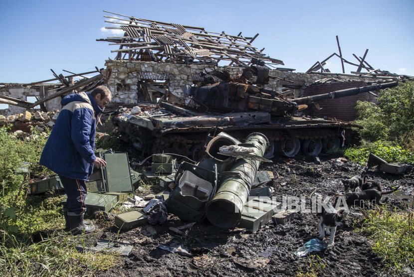 Penduduk lokal Oleksandr melihat tank Rusia yang rusak di dekat rumahnya yang hancur di daerah yang baru saja direbut kembali di dekat Izium, Ukraina, Rabu, 21 September 2022. mendengar tiga suara ledakan di Kota Kharkiv, Ukraina. 