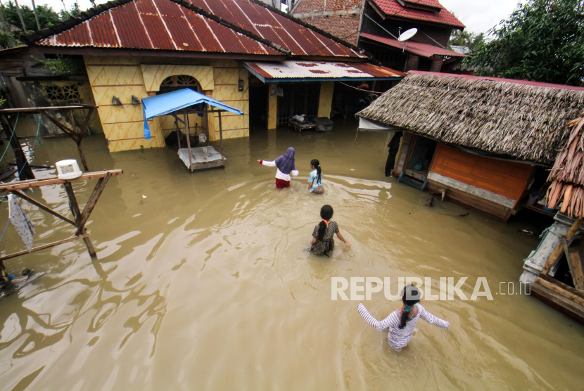 Sejumlah anak warga menerobos banjir untuk masuk kerumahnya di Desa Kumbang, Kecamatan Blang Mangat Lhokseumawe, Aceh.