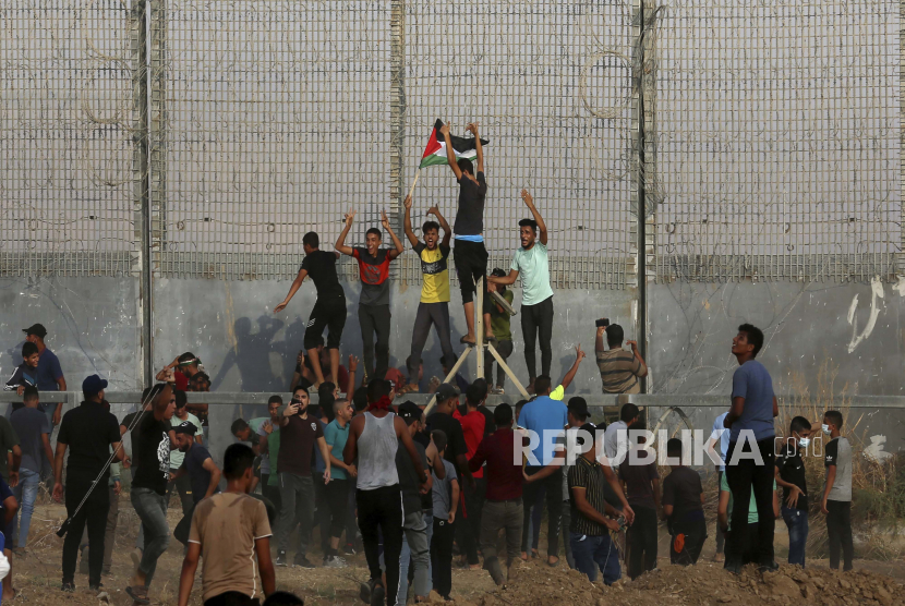 Israel Umumkan Penyelesaian Pagar Penghalang di Gaza. Para pengunjuk rasa mencoba memanjat pagar perbatasan Jalur Gaza dengan Israel, selama protes menandai peringatan serangan pembakaran tahun 1969 di masjid Al-Aqsa Yerusalem oleh seorang turis Australia yang kemudian ditemukan sakit jiwa, di sebelah timur Kota Gaza, Sabtu, 8 Agustus. 21, 2021.