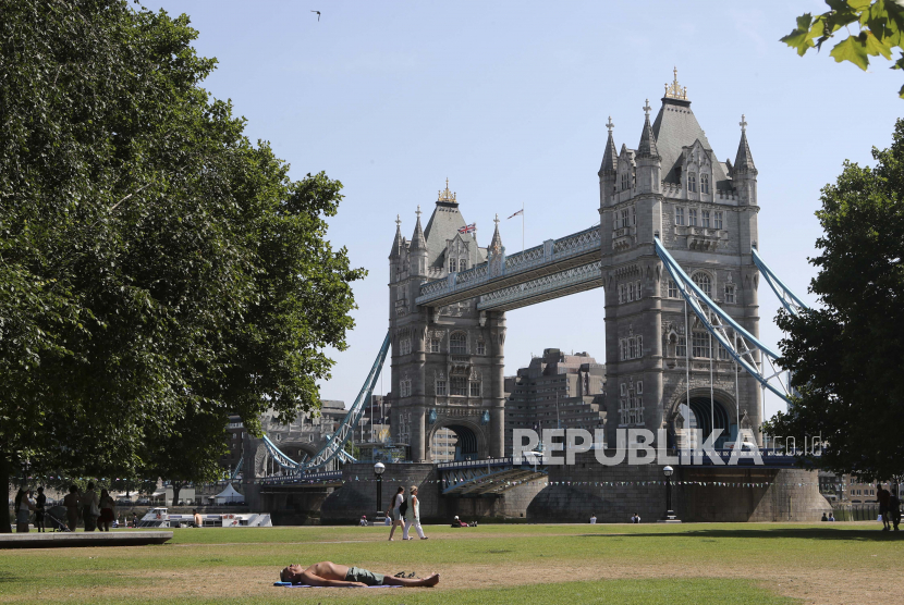Seorang pria berjemur dengan latar belakang Tower Bridge di London, Selasa 19 Juli 2022. Jutaan orang di Inggris terbangun dari malam terhangat di negara itu dan bersiap menghadapi hari ketika suhu bisa memecahkan rekor. Inggris adalah yang terbaru menderita gelombang panas yang membakar Eropa.