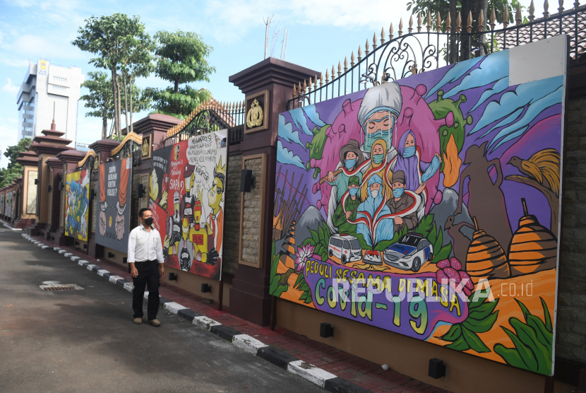 Warga melintas di dekat mural bertema COVID-19 di Jakarta. Menjelang liburan Natal dan Tahun Baru, Pemerintah kembali menaikkan status PPKM di DKI Jakarta menjadi level 3.  (ilustrasi)