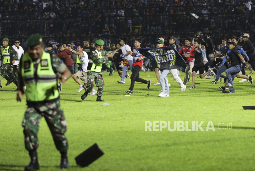  Penggemar sepak bola memasuki lapangan saat personel militer mencoba menghentikan mereka saat terjadi kerusuhan pertandingan sepak bola. (Ilustrasi)