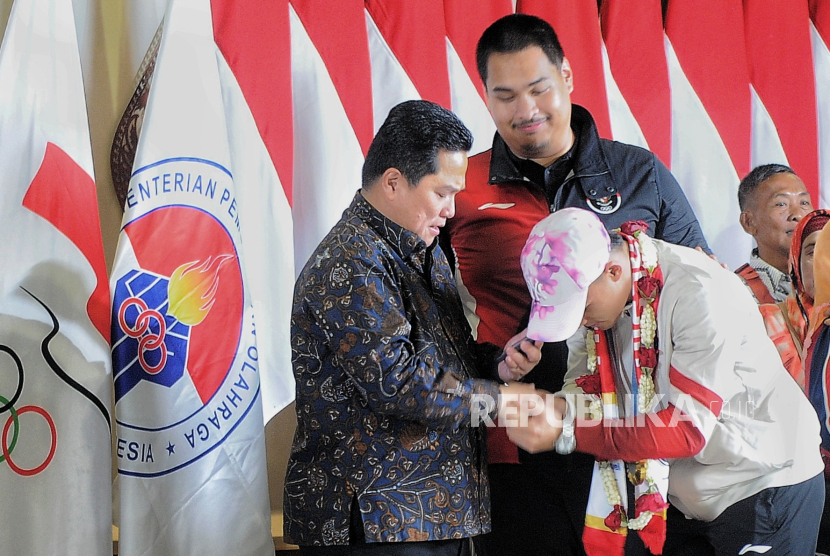 Anggota International Olympic Committee (IOC) Erick Thohir (kiri) bersama Menpora RI Dito Ariotedjo (kanan) menyambut kedatangan atlet angkat besi Rizki Juniansyah (tengah) saat tiba di Bandara Soekarno Hatta, Tangerang, Banten, Selasa (13/8/2024). Rombongan atlet Indonesia yang berlaga pada gelaran Olimpiade Paris 2024 bersama peraih medali emas Veddriq Leonardo dan Rizki Juniansyah tiba di bandara sekitar pukul 22.43 WIB disambut tepuk tangan dari keluarga dan kerabat.