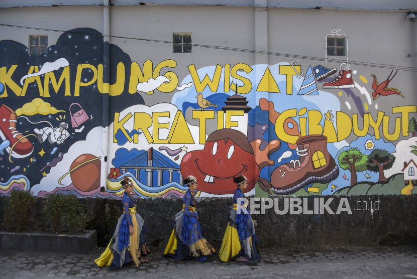 Sejumlah penari melintas di depan mural Kampung Wisata Kreatif (KWK) Sentra Sepatu Cibaduyut, Kota Bandung, Jawa Barat, Senin (13/3/2023). Pemerintah Kota Bandung melakukan aktivasi KWK Cibaduyut dengan harapan dapat meningkatkan dunia pariwisata, perekonomian, dan seni budaya.