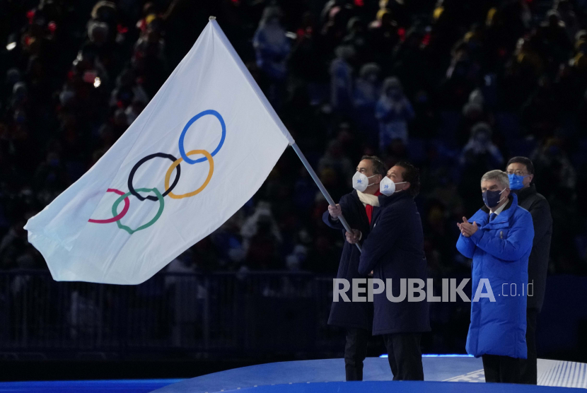 Walikota Milan, Giuseppe Sala, kiri, dan Walikota Cortina, Gianpietro Ghedina mengibarkan bendera Olimpiade saat Presiden Komite Olimpiade Internasional Thomas Bach, kanan, mengawasi berdiri selama upacara penutupan Olimpiade Musim Dingin 2022, Ahad, Februari. 20, 2022, di Beijing.