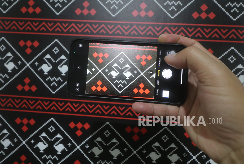 Pengunjung memotret motif tenun Bango Tong-Tong menggunakan gawainya saat pamerkan desain motif tenun ikat di SK Coffe Lab, Kota Kediri, Jawa Timur, Senin (12/9/2022). Pameran yang diselenggarakan Pemerintah Kota Kediri tersebut menampilkan sebelas desain baru sebagai upaya memperkaya motif tenun ikat khas Kediri agar mampu bersaing hingga pasar global. 