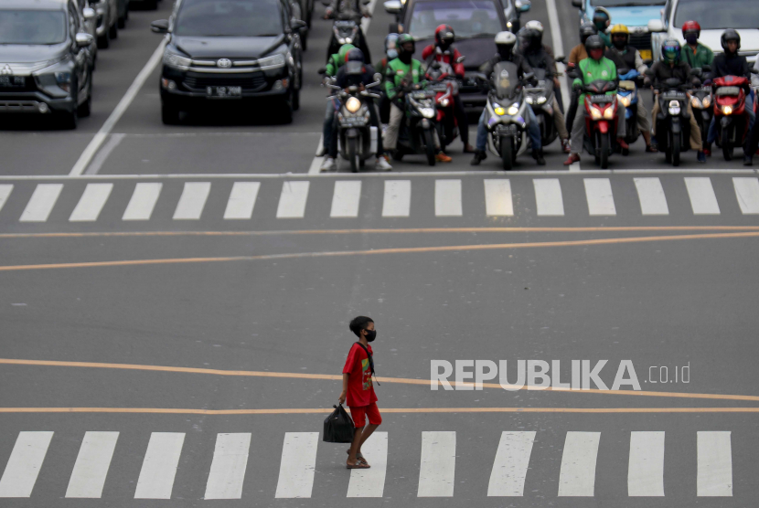  Seorang anak laki-laki memakai masker pelindung saat berjalan melintasi lalu lintas di Jakarta, Rabu (6/1).  Menurut angka terbaru, Indonesia telah mencatat lebih dari tujuh ratus ribu kasus COVID-19 sejak dimulainya pandemi. 