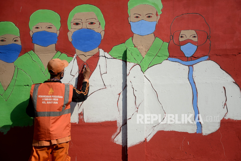 Petugas PPSU Bukit Duri menyelesaikan pembuatan mural terkait tenaga kesehatan yang berjuang di tengan pandemi virus Corona di Bukit Duri, Jakarta. IDI mencatat pandemi Covid-19 telah mengakibatkan 100 tenaga kesehatan (nakes) meninggal dunia. 