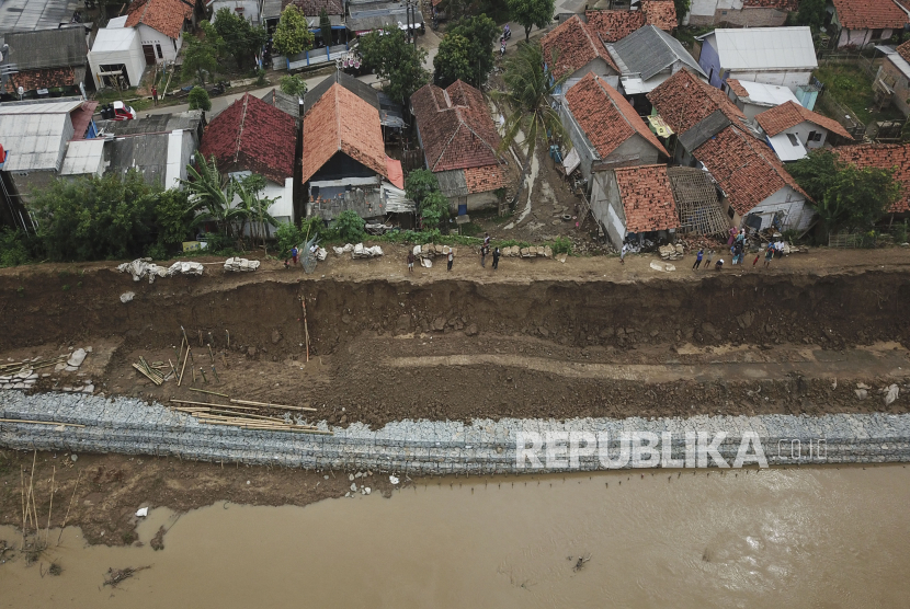 Foto udara rumah warga yang terkena dampak tanggul aliran sungai Citarum yang amblas di Desa Lenggahjaya, Cabangbungin, Kabupaten Bekasi, Jawa Barat, Rabu (12/1/2022). Tanggul yang amblas  akibat curah hujan yang tinggi sepanjang 350 meter merusak tiga rumah warga. 