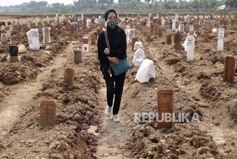  Seorang wanita berjalan di antara kuburan korban COVID-19 di Pemakaman Rorotan di Jakarta, Indonesia, Rabu, 7 Juli 2021. 