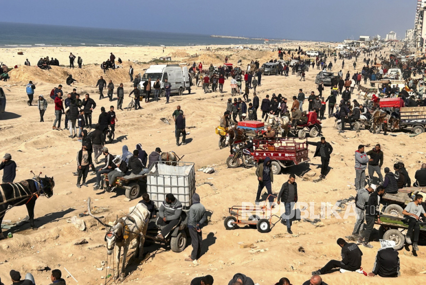 Warga Palestina menunggu bantuan kemanusiaan di tepi pantai Kota Gaza, Jalur Gaza, Ahad, 25 Februari 2024.