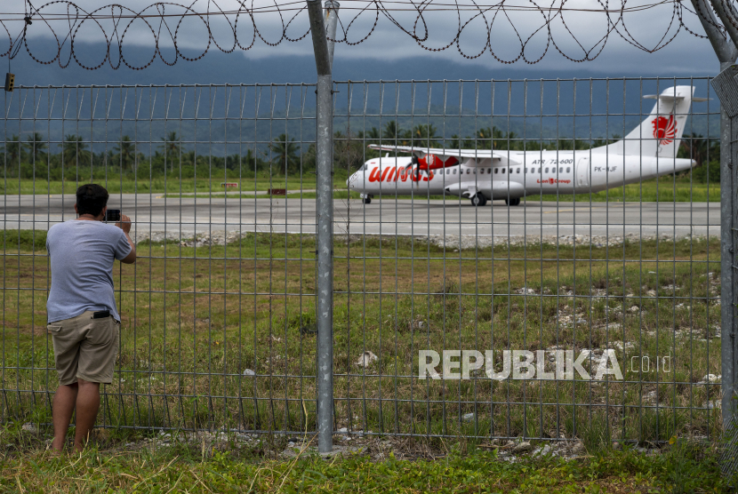 Warga memotret sebuah pesawat yang akan terbang ke Makassar di Bandara Kassiguncu, Poso Sulawesi Tengah, Jumat (1/10). Pengamat penerbangan Gatot Rahardjo mengungkapkan adanya holding aviasi dan pariwisata dikhawatirkan akan mempersempit persaingan bisnis.