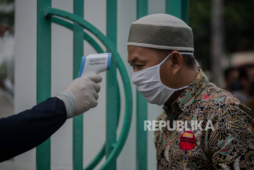 Petugas masjid mengecek suhu tubuh jemaah. Ilustrasi