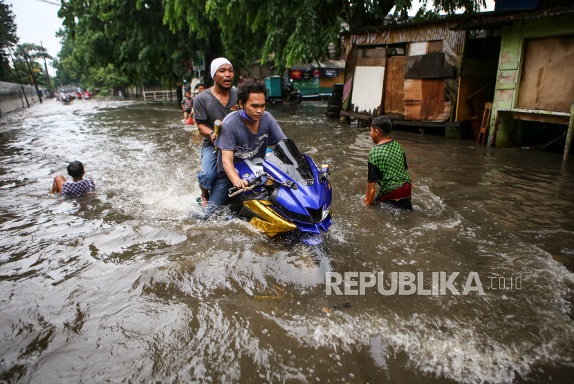Pengendara motor melintasi banjir di kawasan Manis, Jatiuwung, Kota Tangerang, Banten, Ahad (22/11/2020). Hujan deras yang mengguyur kawasan tersebut serta sistem drainase yang buruk menyebabkan banjir hingga satu meter. 