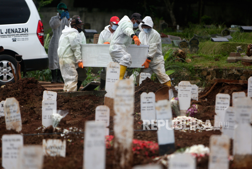 Makam jenazah Covid  di TPU Bambu Apus yang rencananya akan menerapkan pemakaman moderen. Foto, kerja yang mengenakan jas hazmat membawa peti mati korban Covid-19 saat pemakaman di TPU Bambu Apus Jakarta.