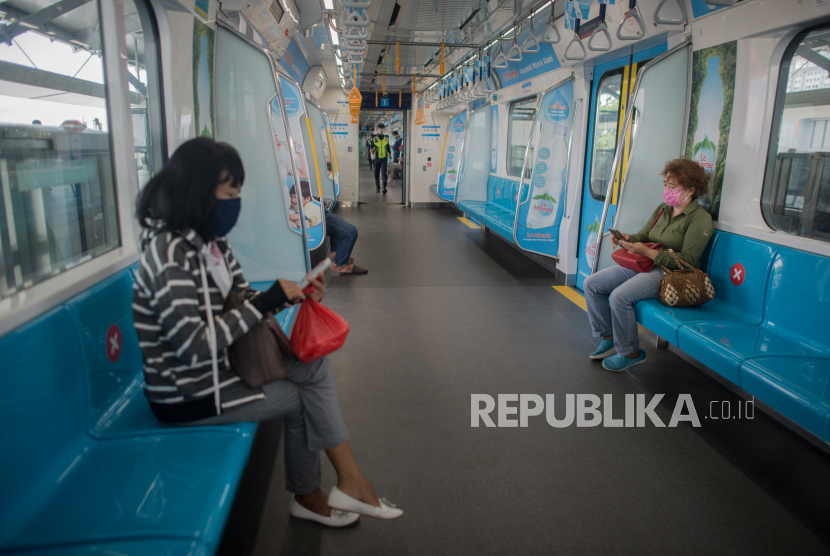 Penumpang menggunakan masker saat menaiki kereta Moda Raya Terpadu (MRT).