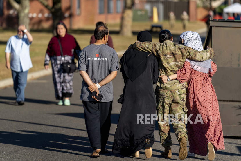  Seorang anggota militer wanita merangkul dua wanita pengungsi Afghanistan setelah mereka berbicara dengan Menteri Pertahanan Lloyd Austin ketika dia mengunjungi sebuah kamp pengungsi Afghanistan di Pangkalan Bersama McGuire Dix Lakehurst, N.J., Senin, 27 September 2021.