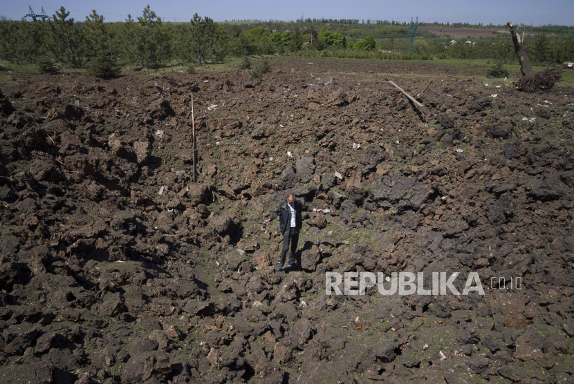 Seorang pria berdiri di kawah ledakan setelah serangan udara Rusia di Bakhmut, wilayah Donetsk, Ukraina, Sabtu, 7 Mei 2022.